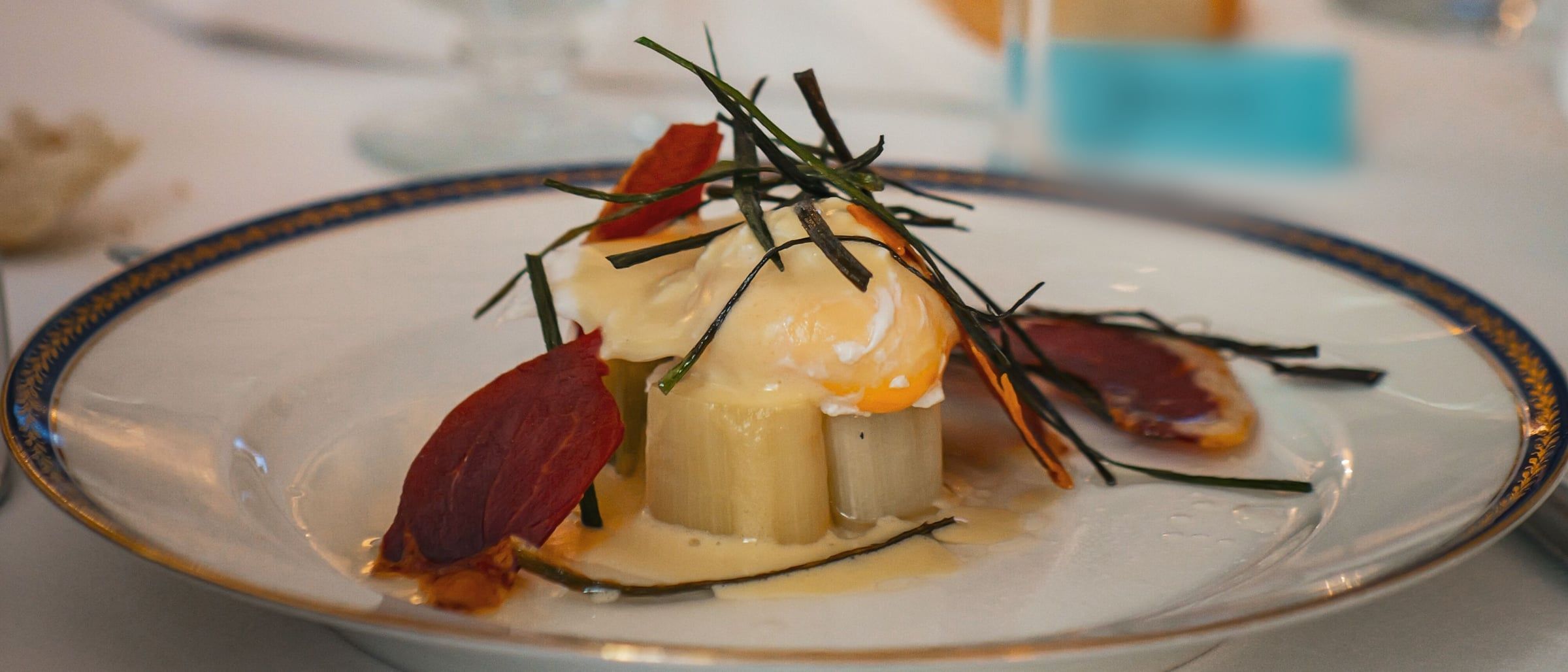 Poireaux vinaigrette avec son œuf poché nappé de sauce hollandaise, couvert d’une chips de lard et vert de poireaux frit